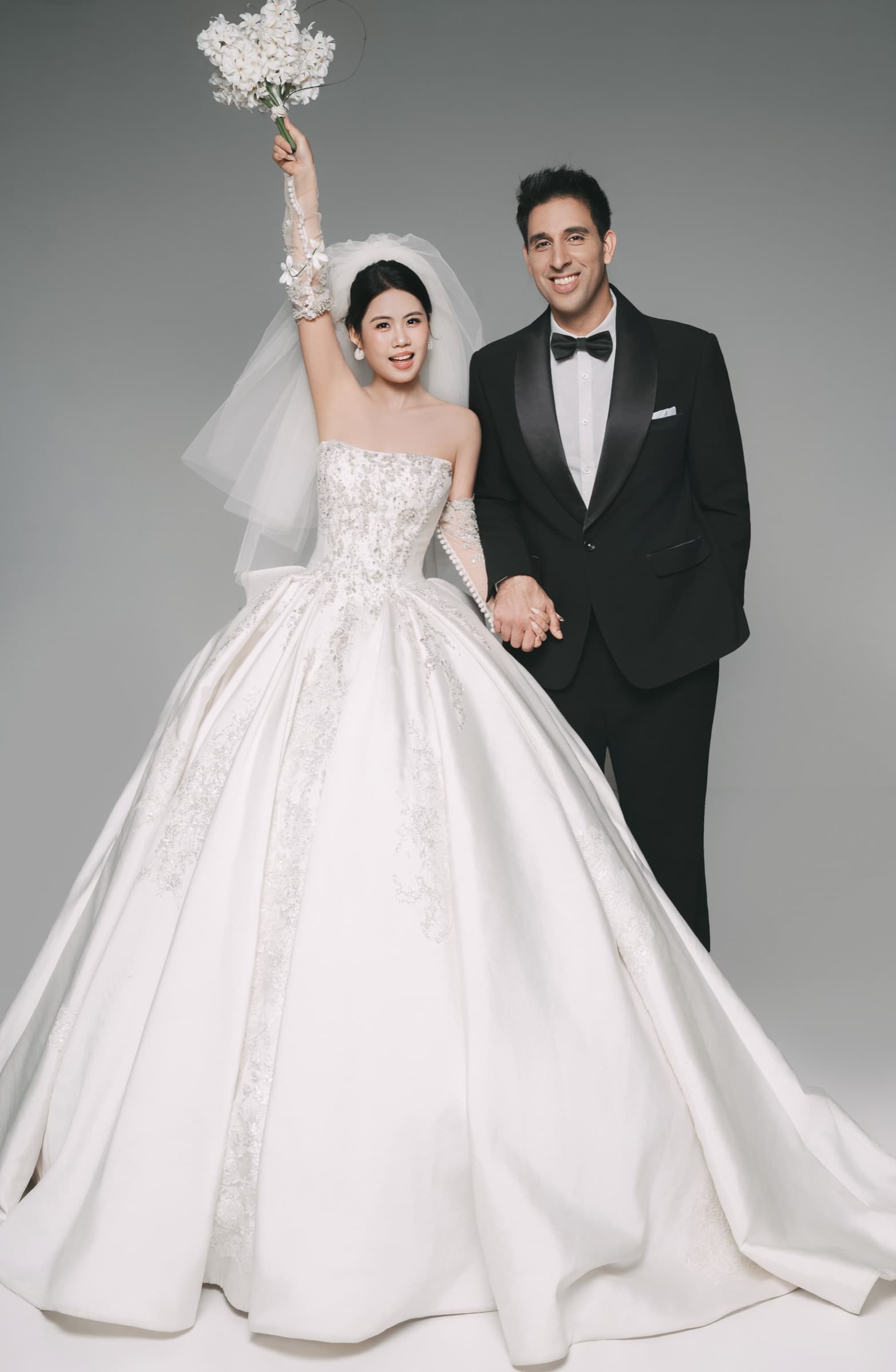 The couple smiling together, the bride raising her bouquet